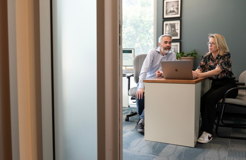 Alex Pico and Kristina Hanspers sitting at a desk discussing something over a laptop