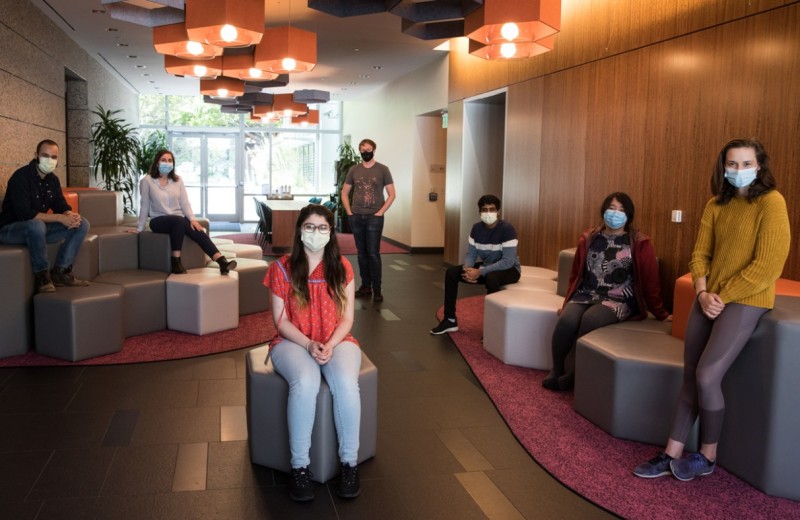 Gladstone scientists sitting 6 feet a part from each other wearing masks in the Gladstone lobby
